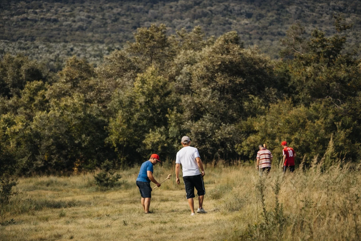 Players walking through a bushveld clearing on the Ancient Golf course at Shelter Rock, Magaliesberg ridge in the distance.