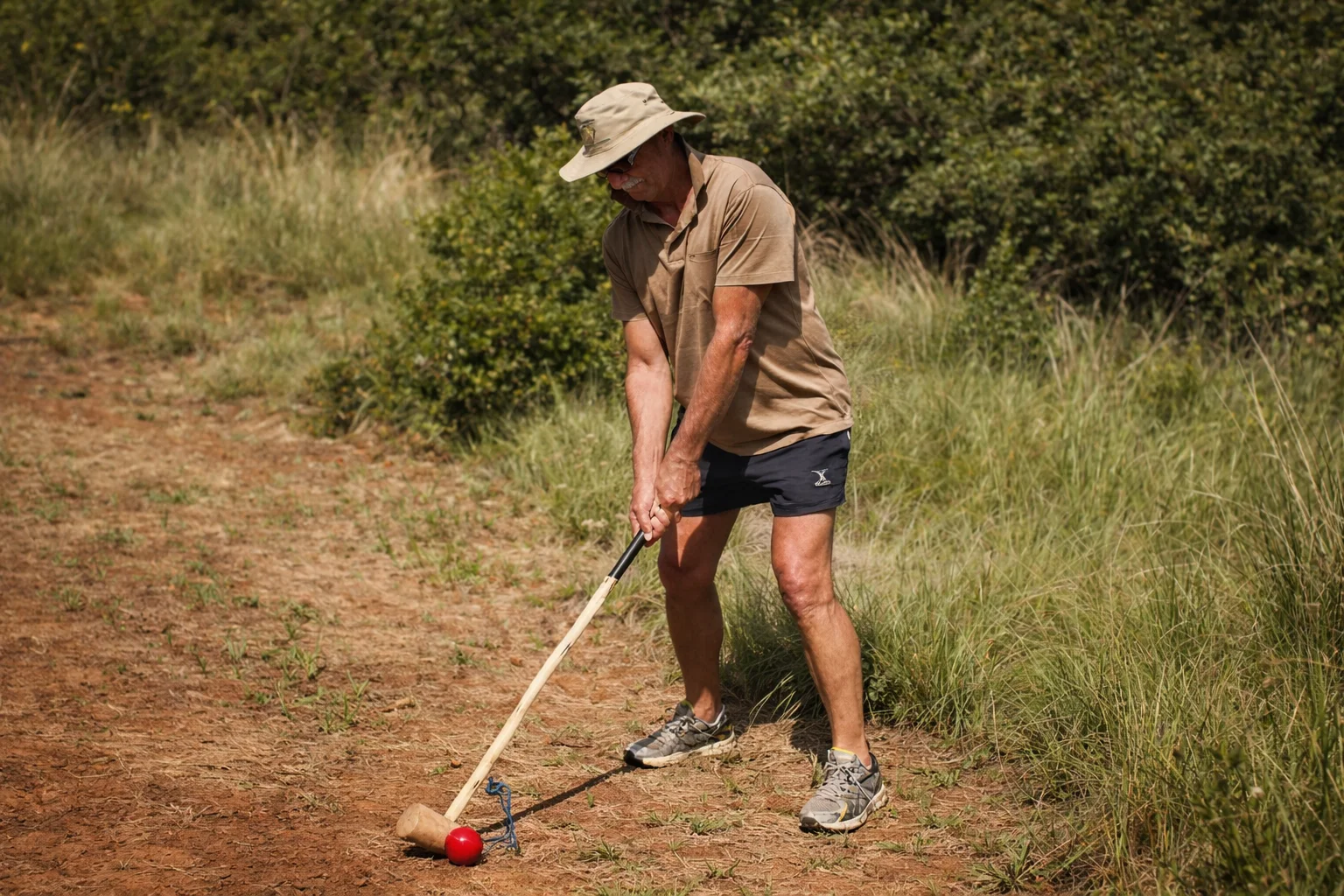 A player lining up a shot with a handcrafted knobkierie on the Ancient Golf course at Shelter Rock in the Magaliesberg.